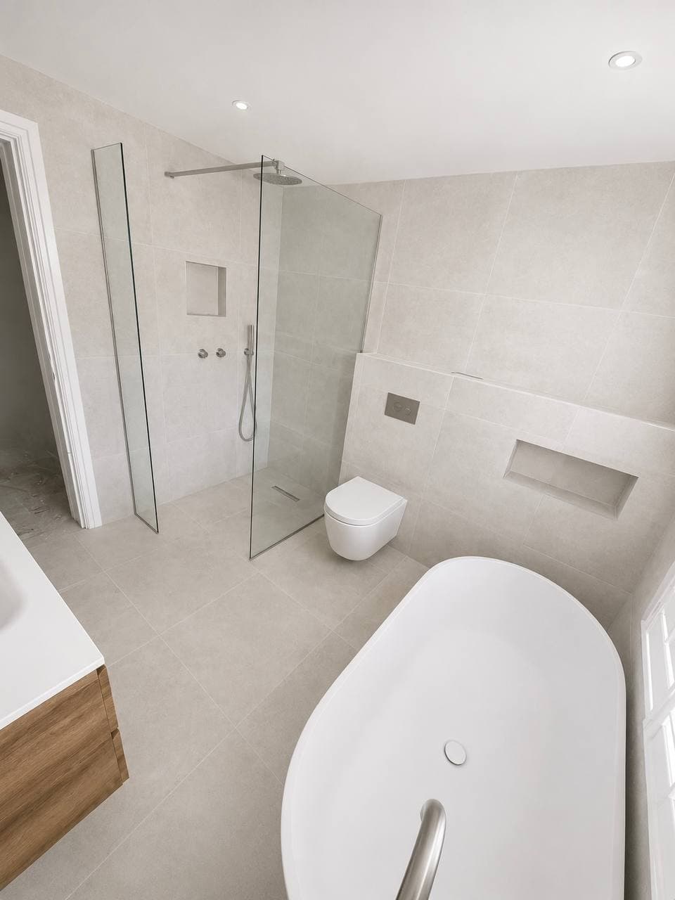 Walk-in shower, wall-mounted toilet and freestanding bath in a contemporary bathroom
